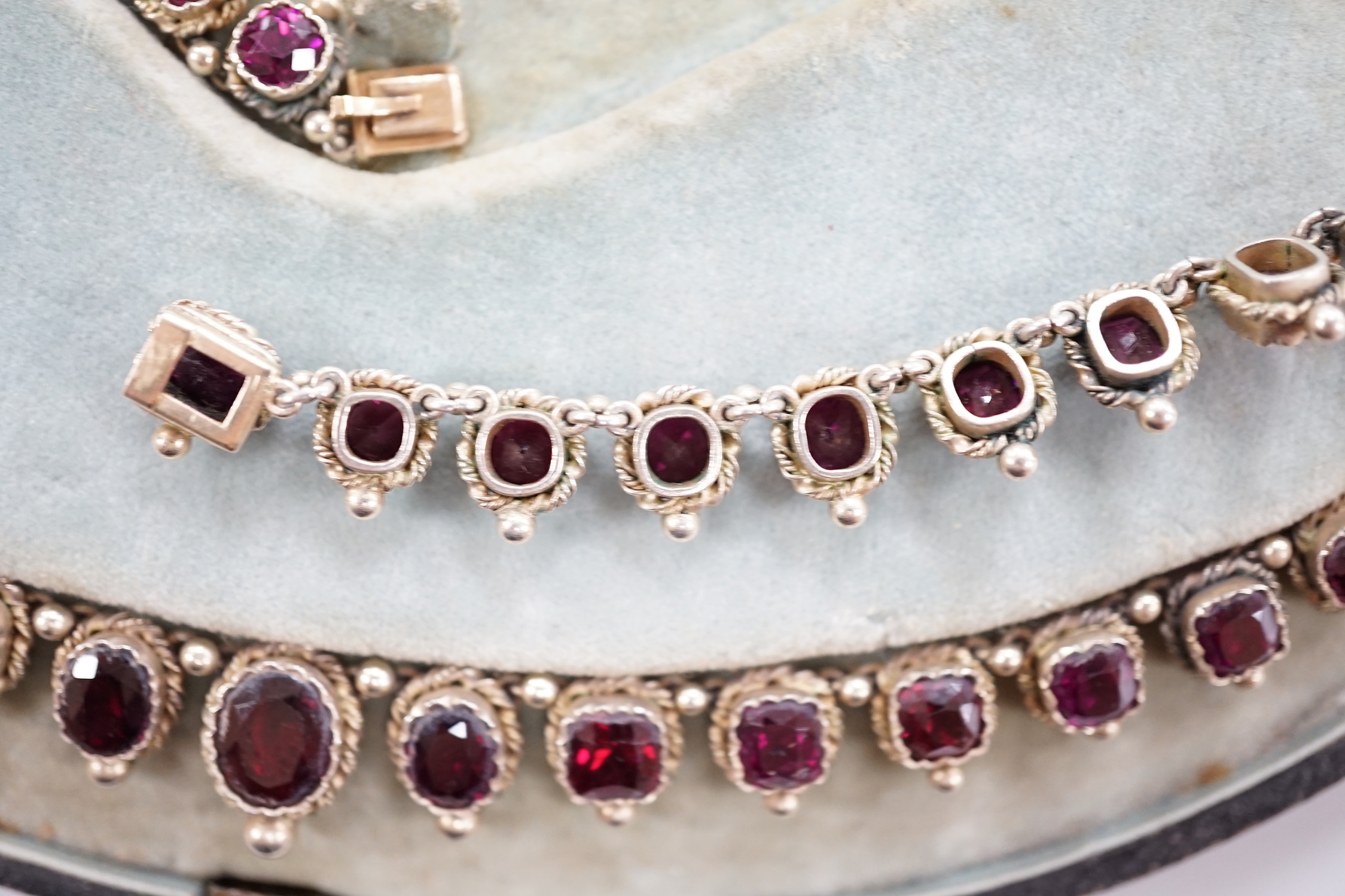 A cased 19th century gilt white metal and graduated oval and square cut garnet set fringe necklace, lacking drop, 37cm.